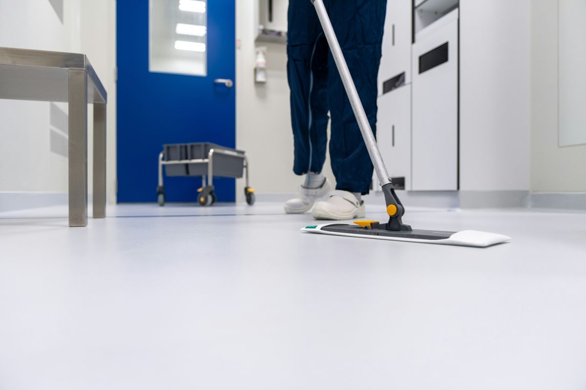 Cleaner mopping a bright, clean office corridor floor