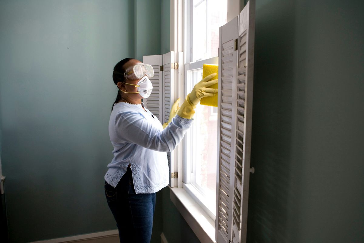 Cleaner in gloves wiping an internal window frame